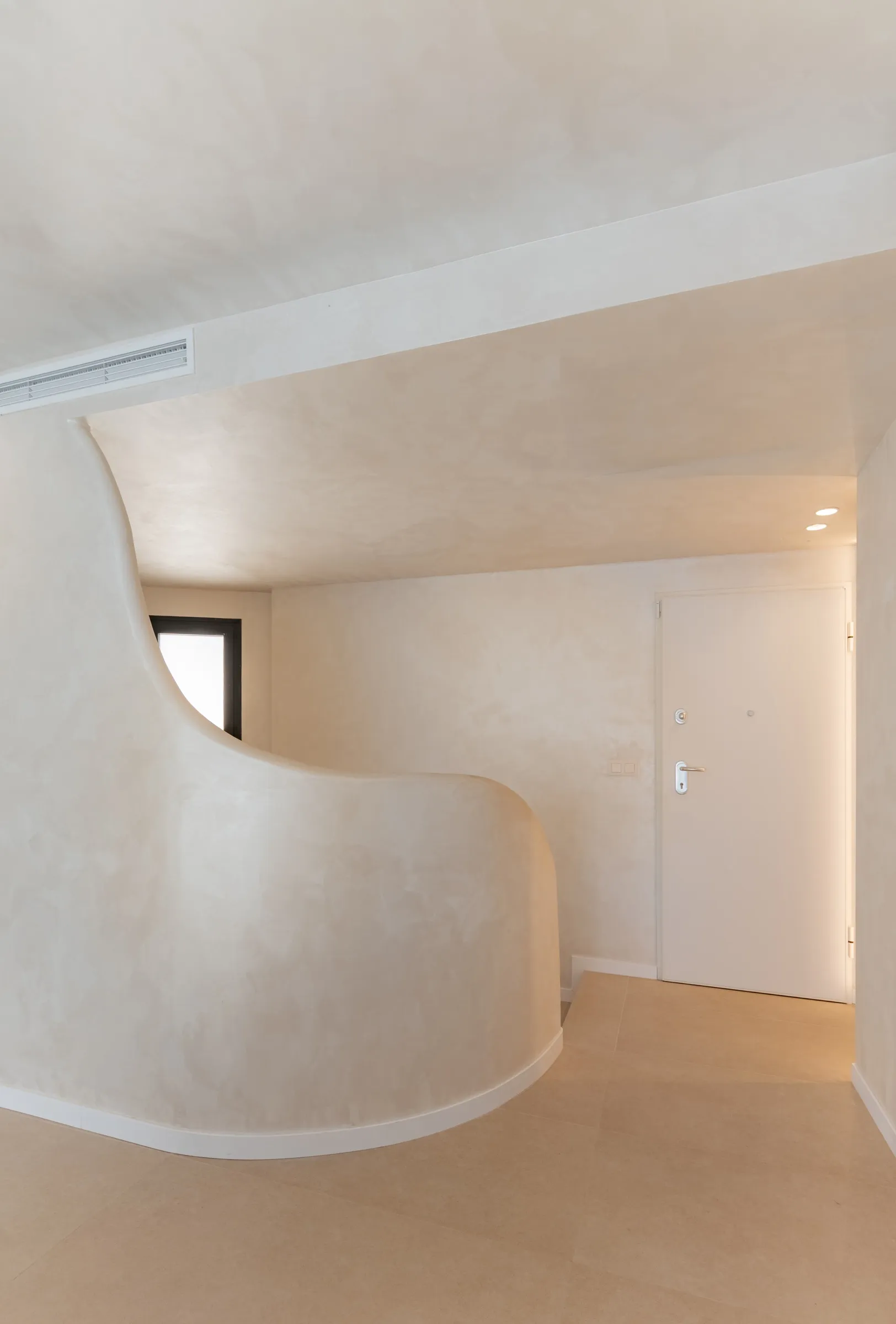Recibidor con mueble curvo de obra y luz indirecta