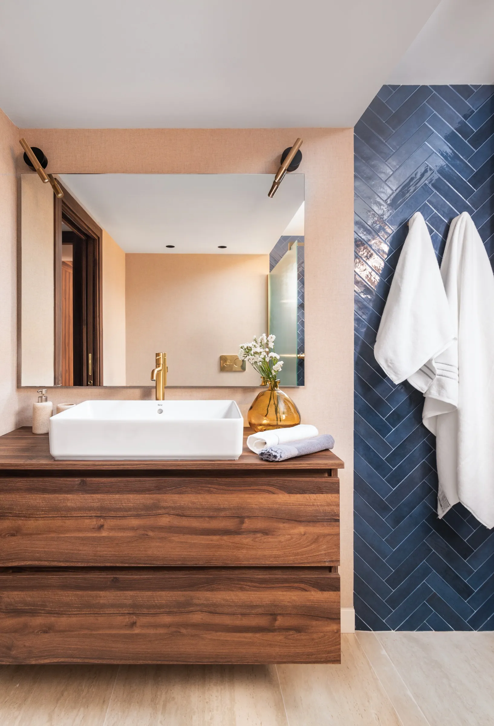 Mueble de baño de nogal con lavabo blanco y azulejo azul en espiga