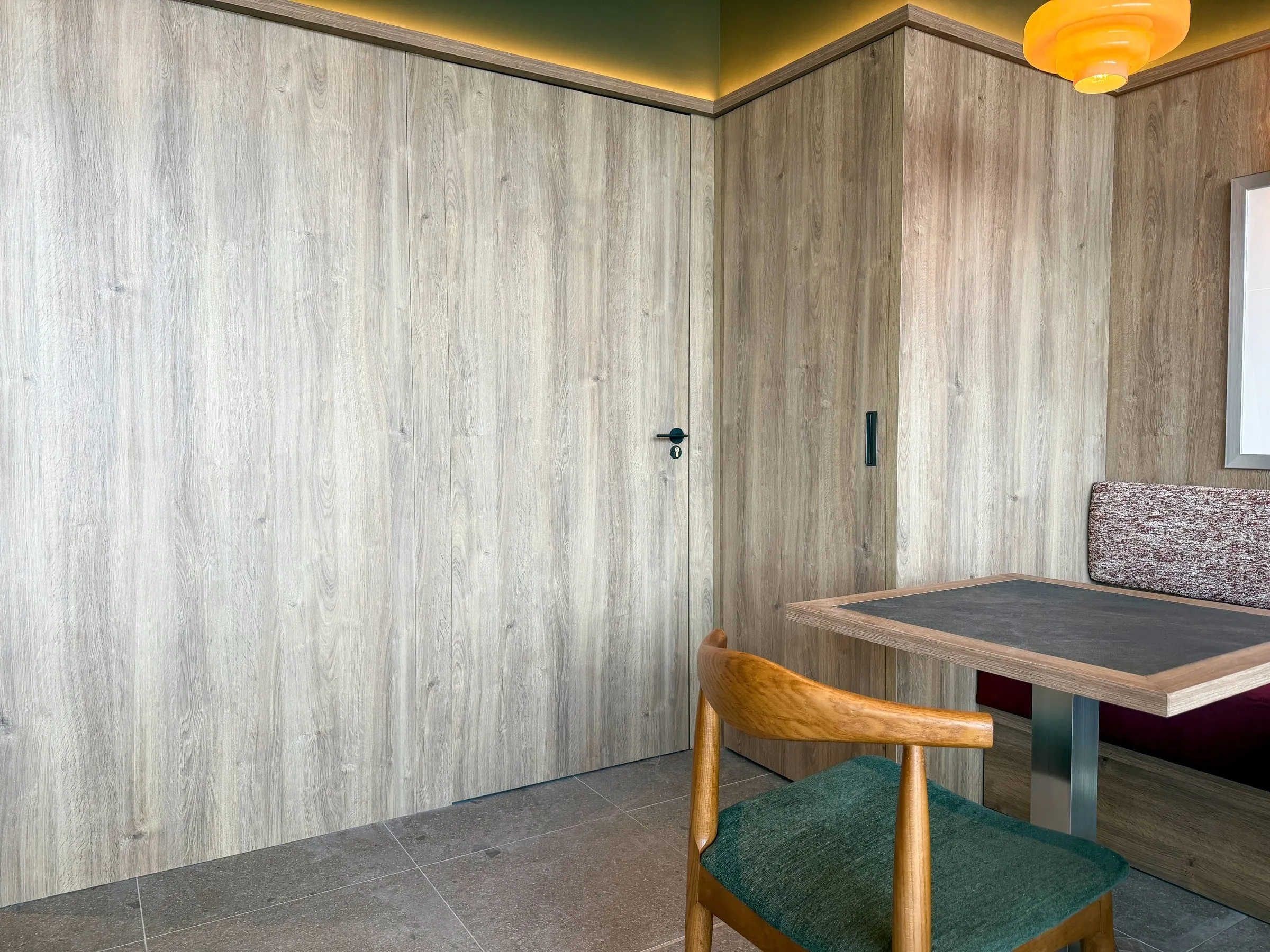 Salón del hotel con banco corrido, láminas enmarcadas y panelado de roble