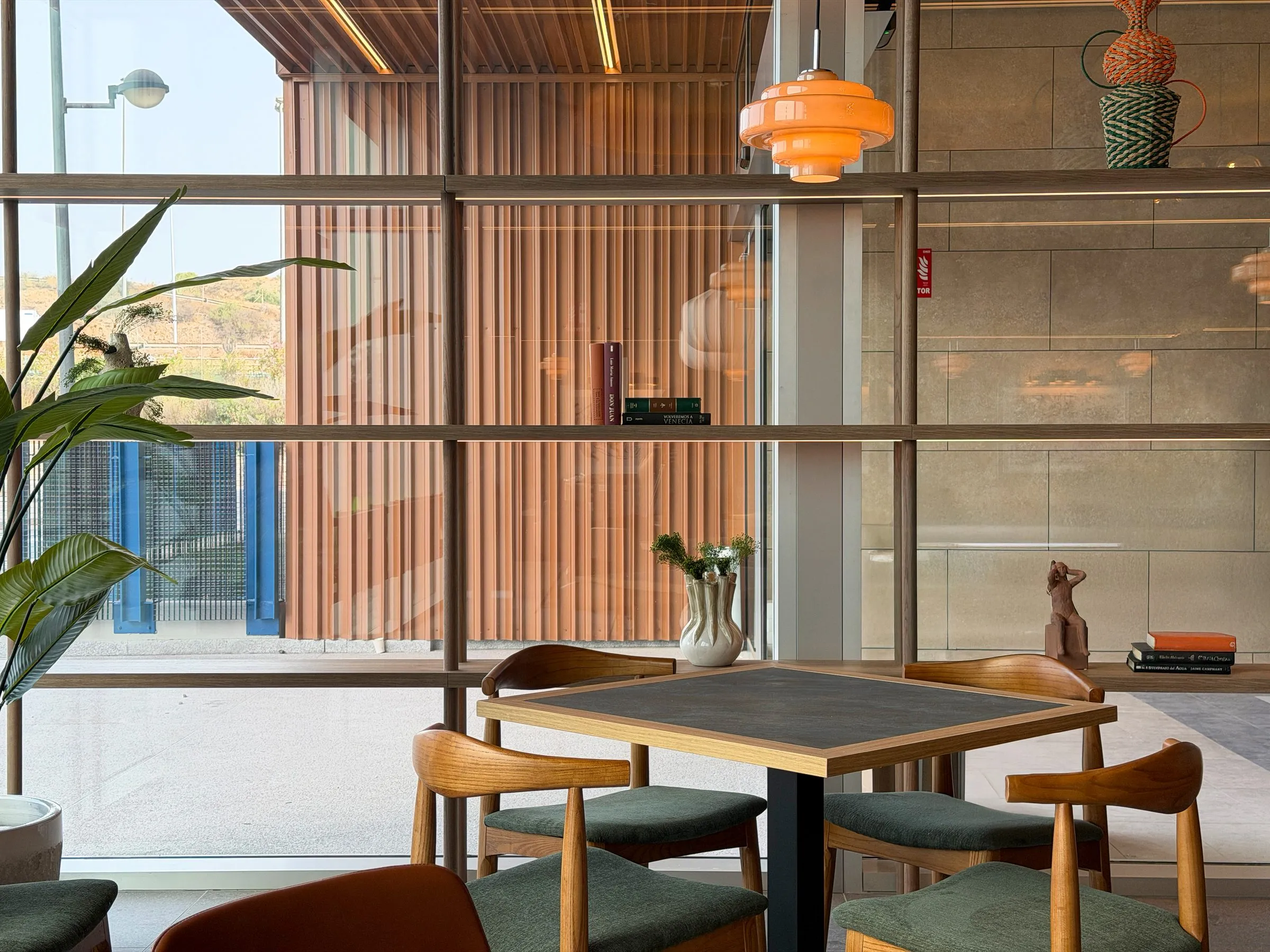 Mesas de la cafetería junto a las celosías de madera del hotel