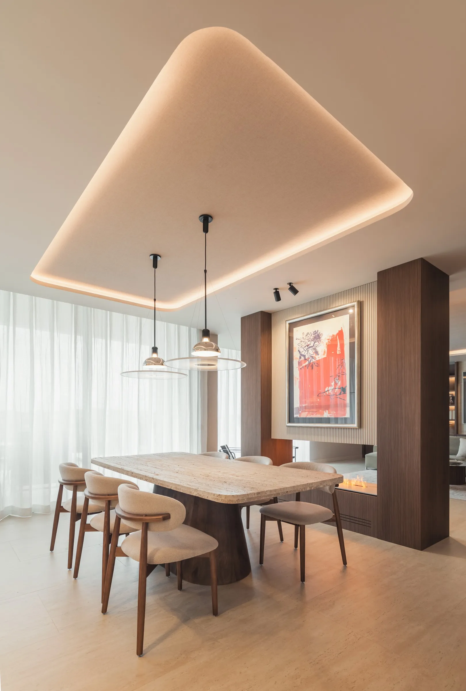 Comedor con mesa de madera clara y falso techo de luz cálida
