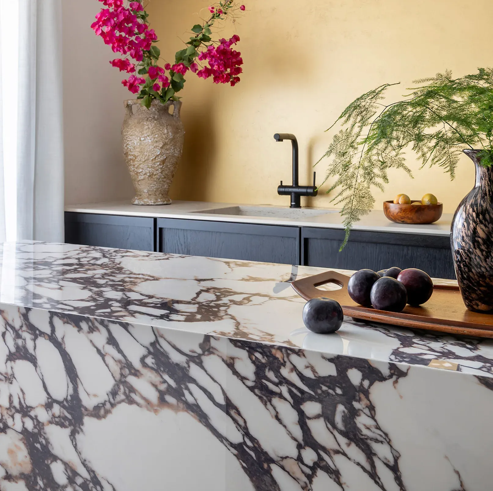 Cocina Umbría con frentes en roble oscuro wengue, isla en xtone y panelado en laca oro