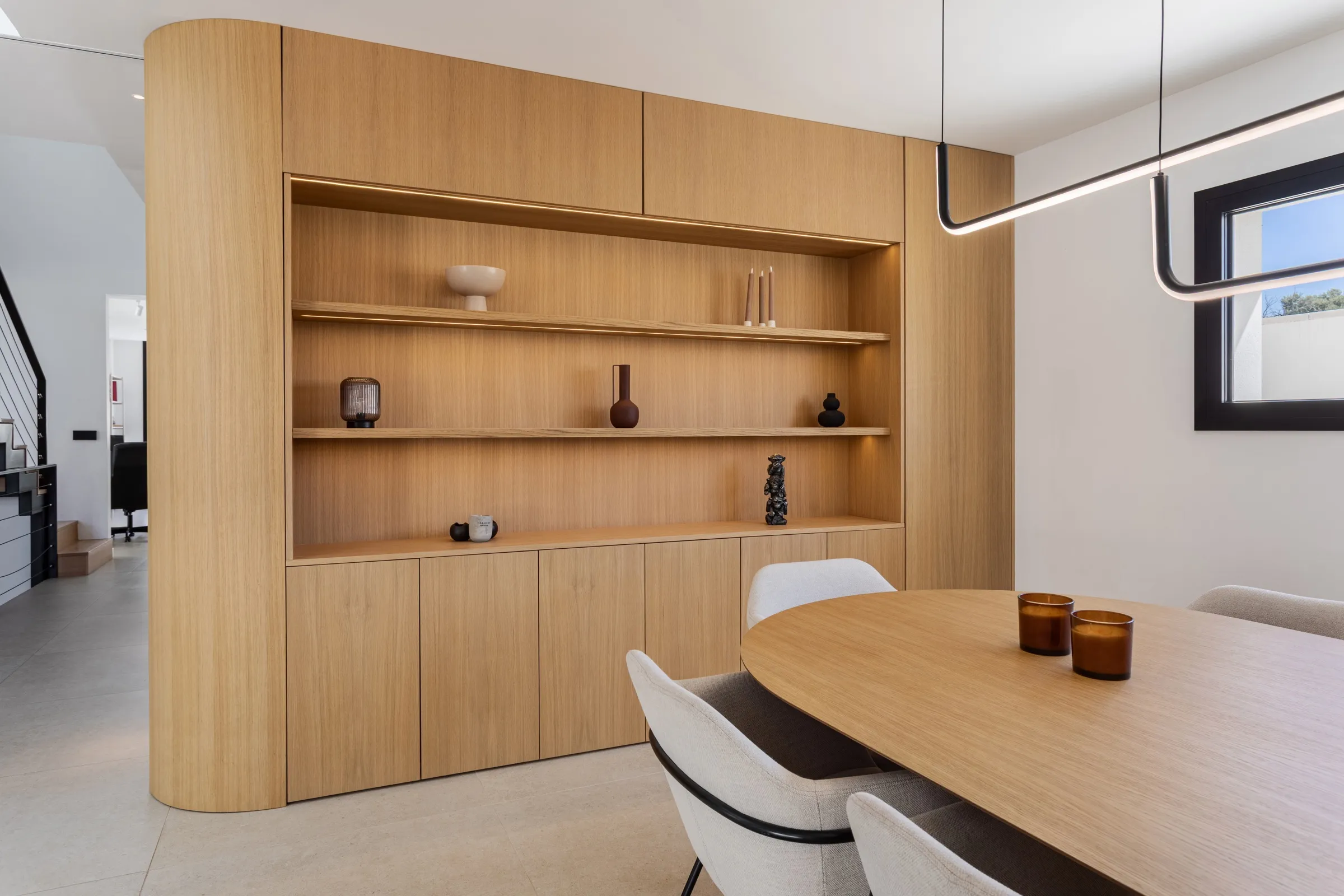 Comedor con librería de volumen curvo de roble a medida